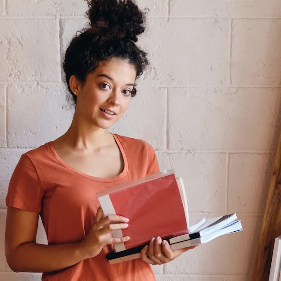 Smiling college student with notebooks, ready to embrace the academic and social challenges of college, representing the preparedness fostered by Ginger-U's College Transition Wellness program.