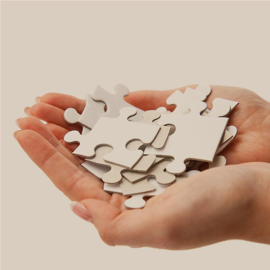 Hands holding puzzle pieces against a neutral background, symbolizing the process of solving health mysteries with Ginger-U's Mystery Symptoms program.