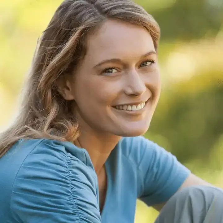Smiling woman in a natural setting, representing the health and vitality supported by Ginger-U's pure, high-quality supplements with full transparency and superior ingredients.
